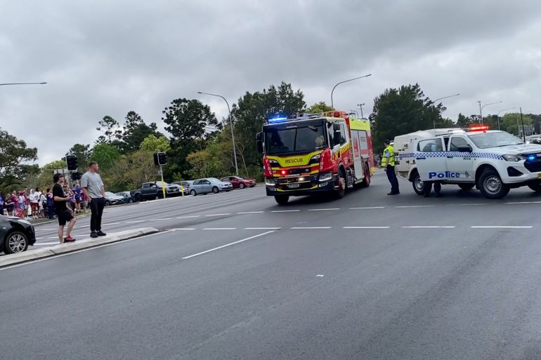 Emergency vehicles at scene of crash with crowds and police tape
