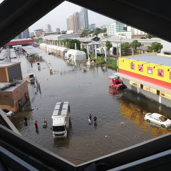 Rescue boats on a flooded road with emergency personnel standing by