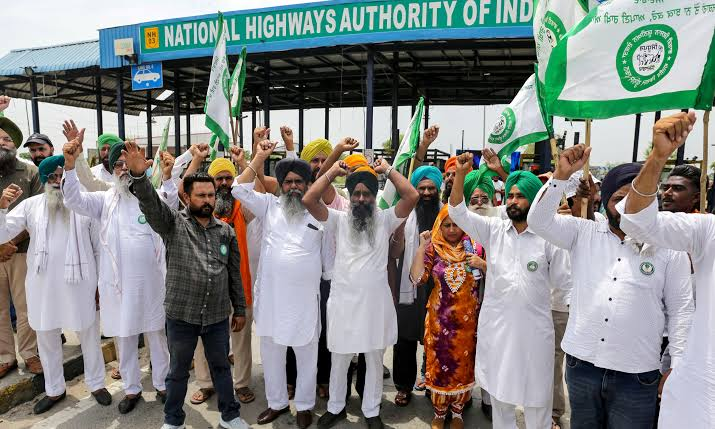 Farmers sitting on road during protest in Punjab with tractors and langar tents