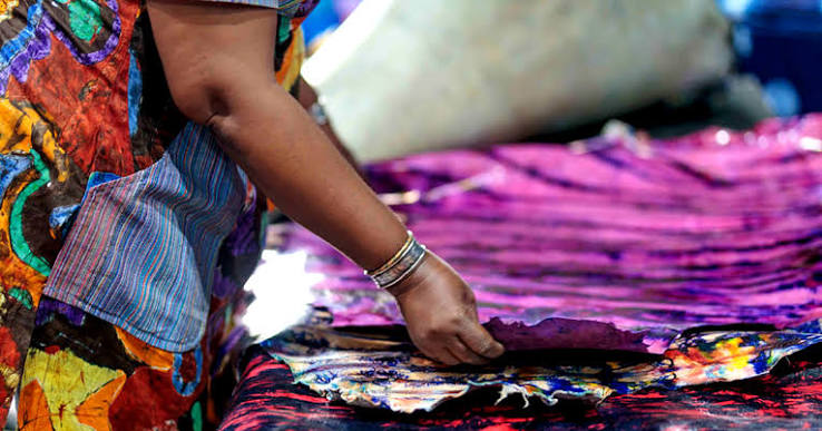 Visitors examining traditional woven textiles at a display table during the Alt.FFF fair in Accra