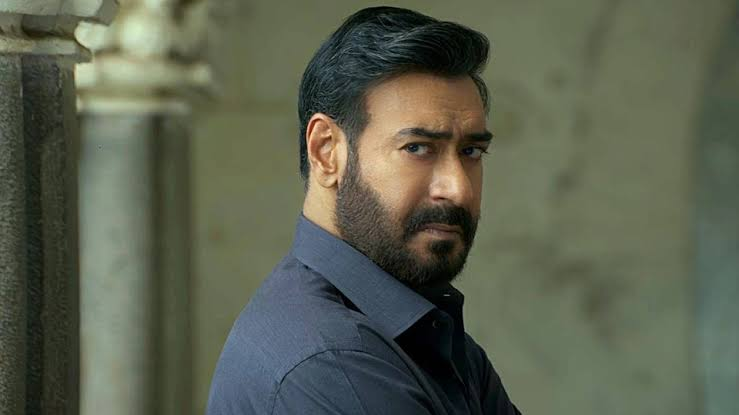 Ajay Devgn in Drishyam poster with crowded cinema booking screen in background